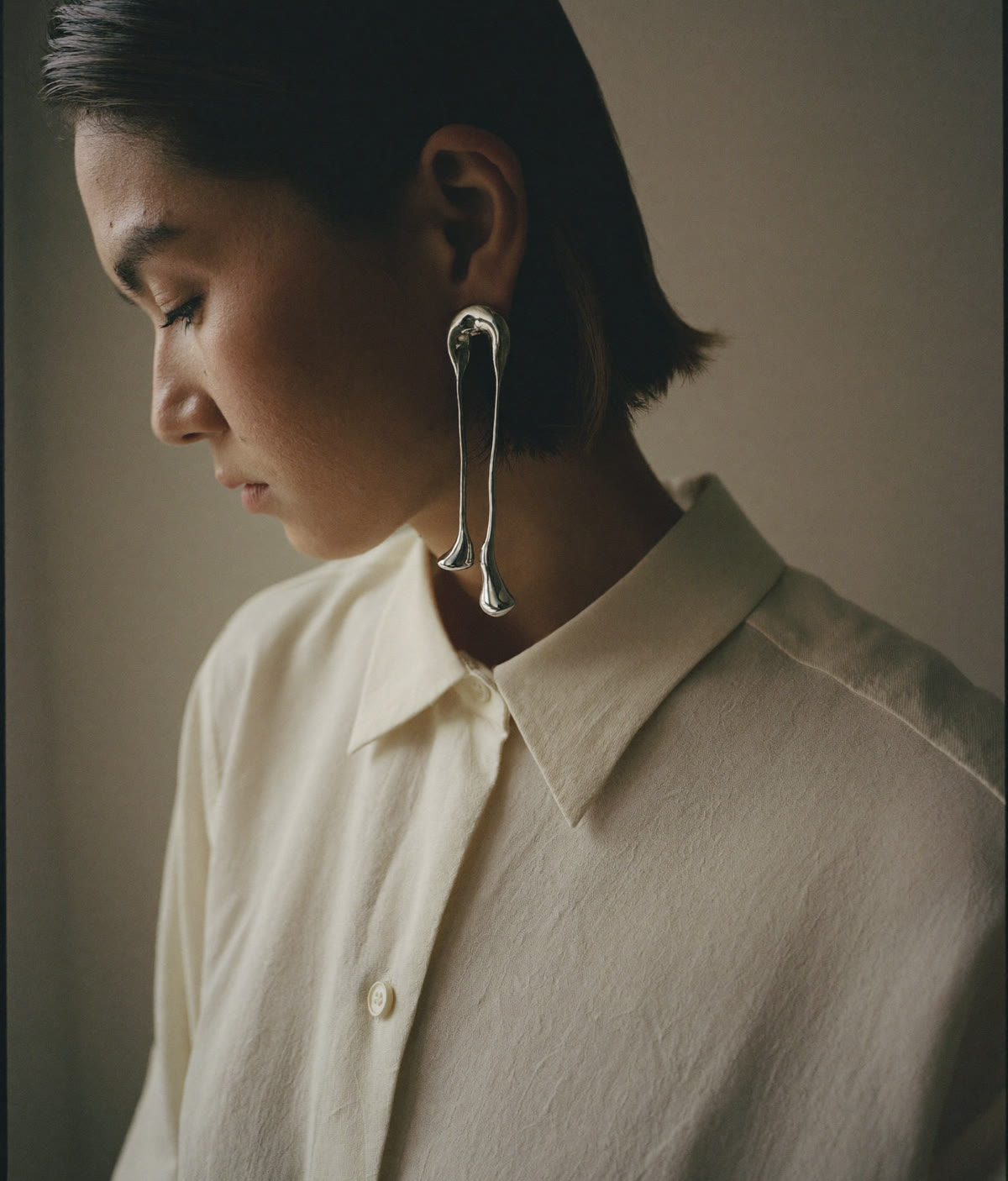 A long silver drop earring in profile