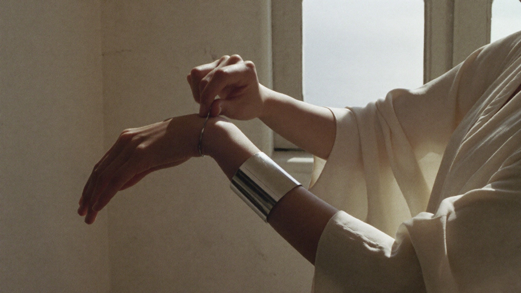 Hands fastening a wide silver cuff